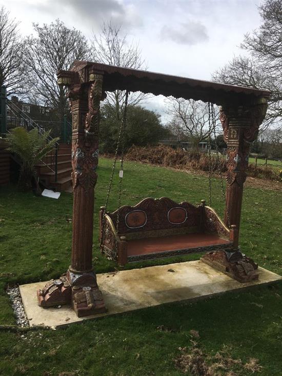 A large Florentine style carved wood garden swing